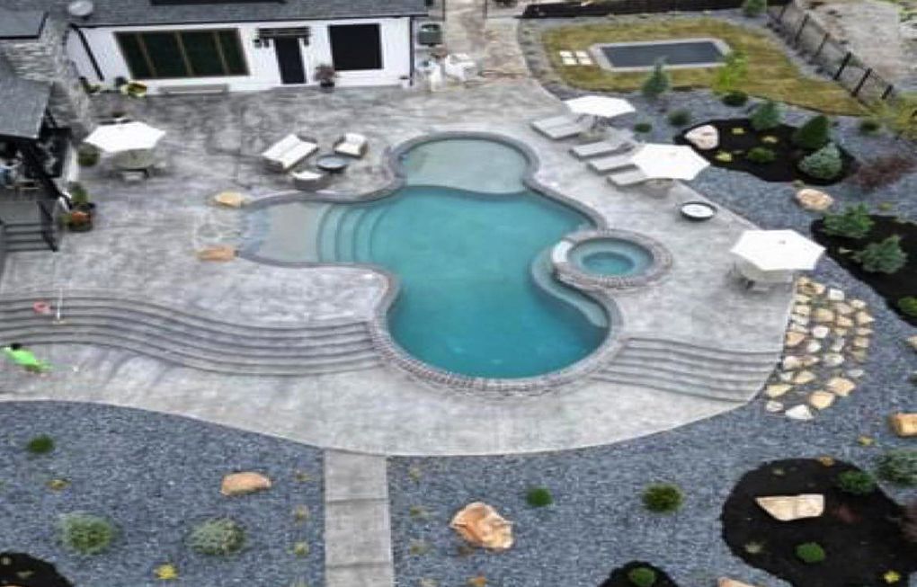 an aerial view of a large swimming pool in the backyard of a house