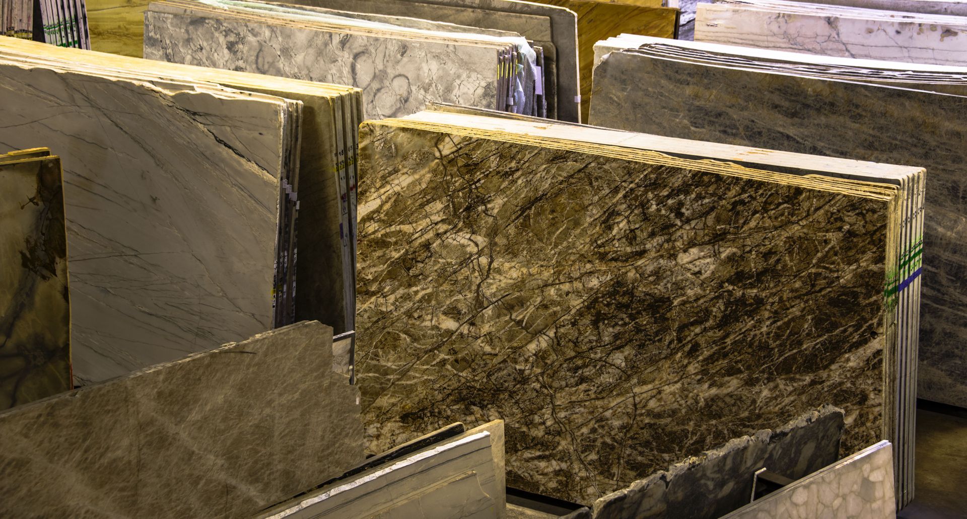 Stacks of various marble slabs in a warehouse, showcasing different patterns and colors.