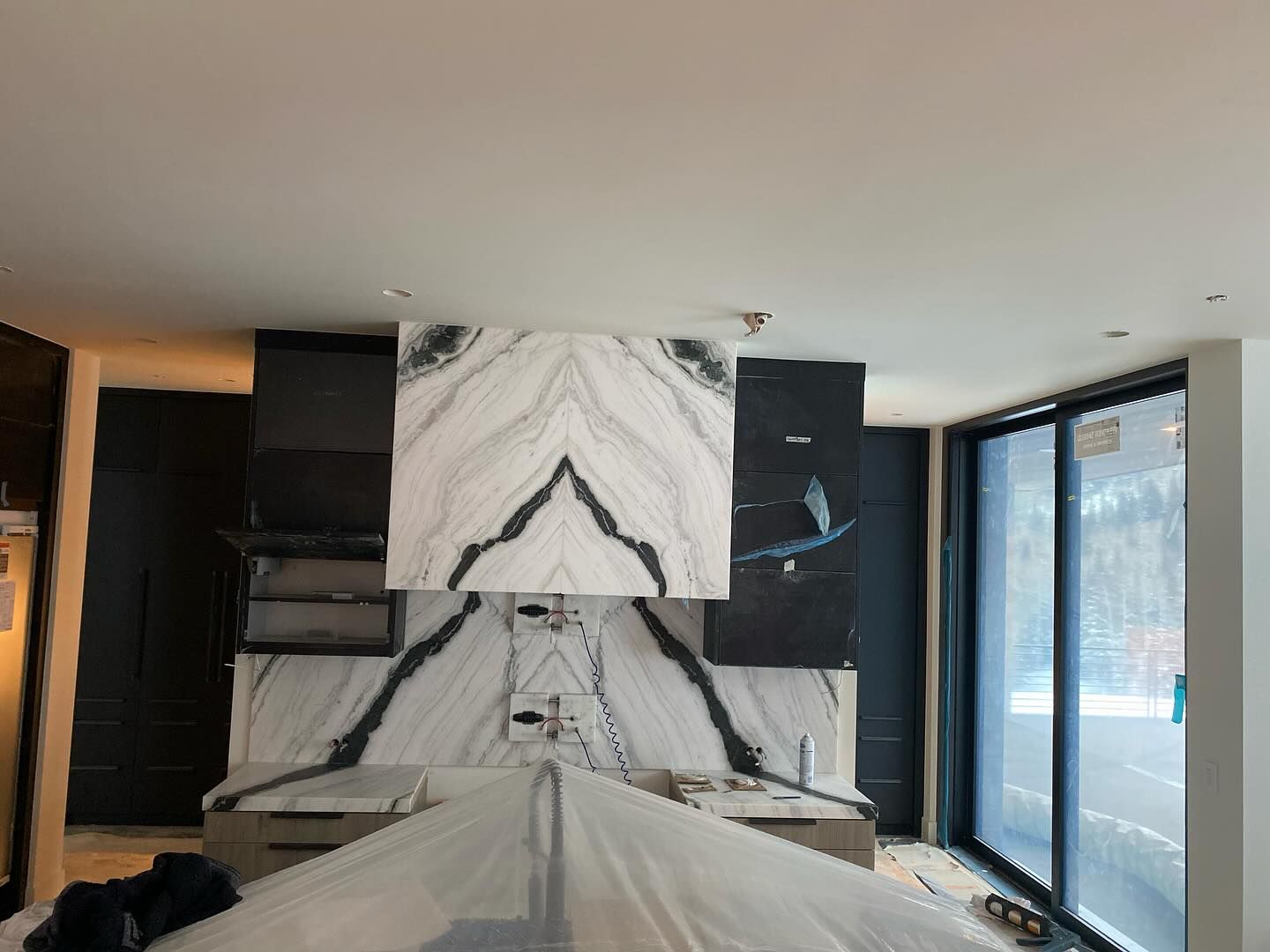 Kitchen renovation with marble backsplash, cabinets, and a window.