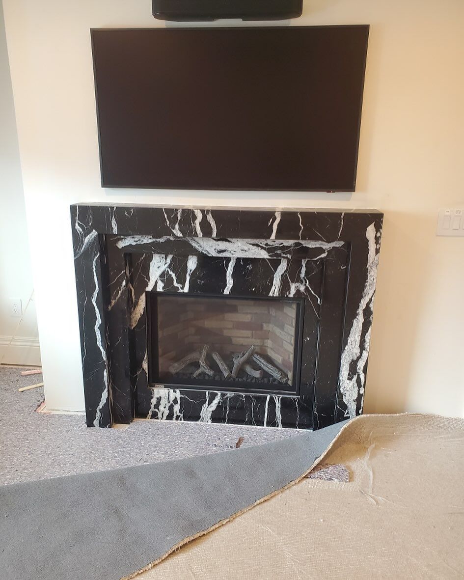 Black marble fireplace with a television mounted above it.