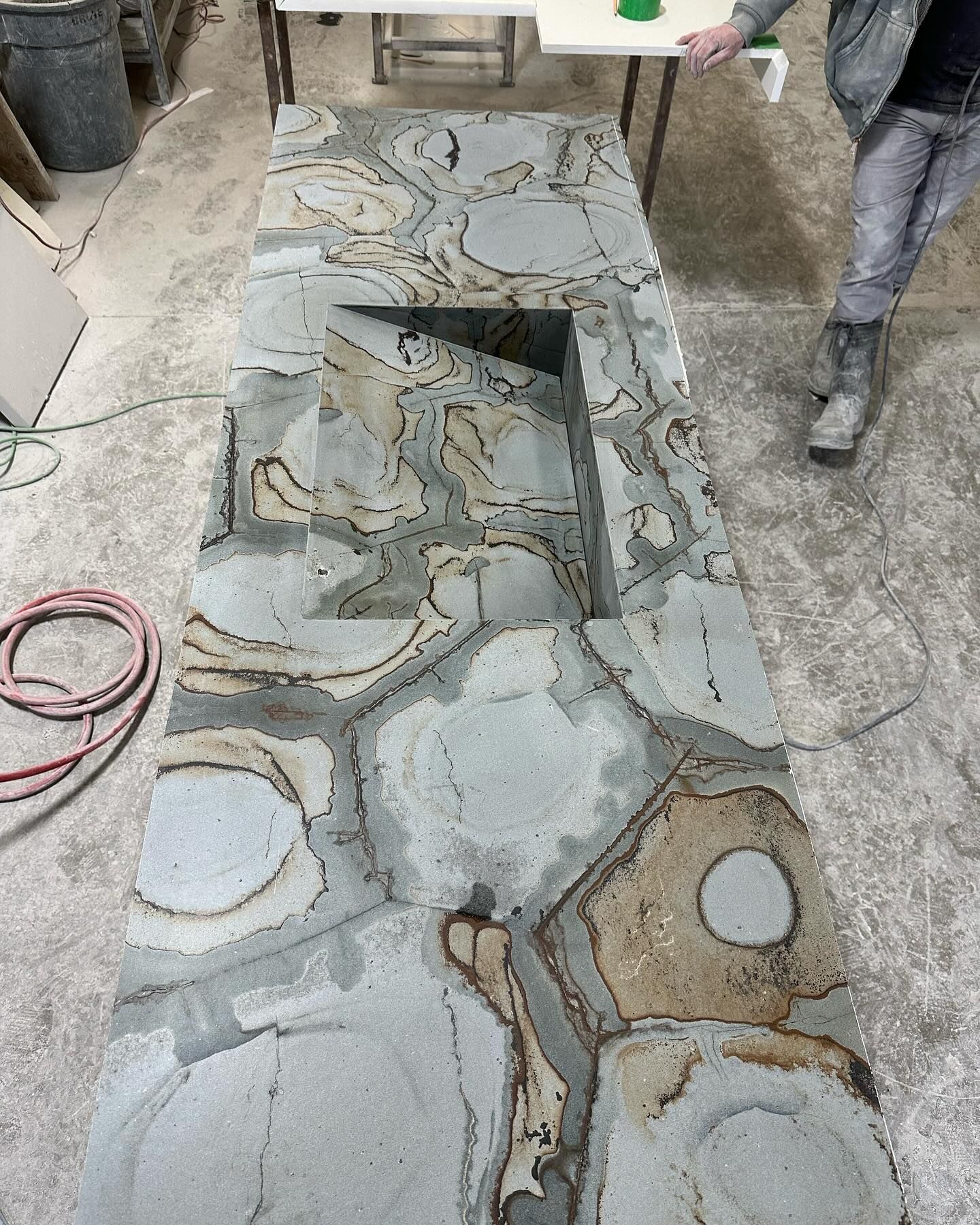 Stone countertop with irregularly shaped sections, gray, tan, and brown, with a built-in rectangular opening.