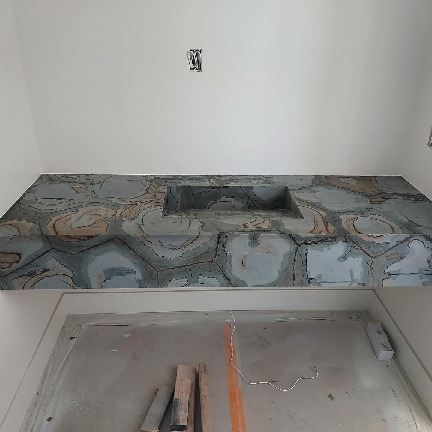 Stone countertop with a rectangular basin, in a white cabinet.