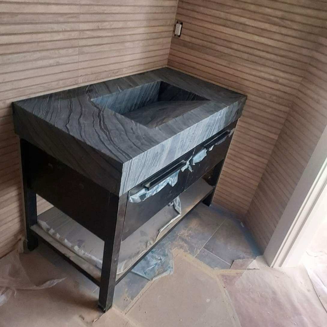 Dark stone bathroom vanity with integrated sink, black frame, two drawers, and a lower shelf.