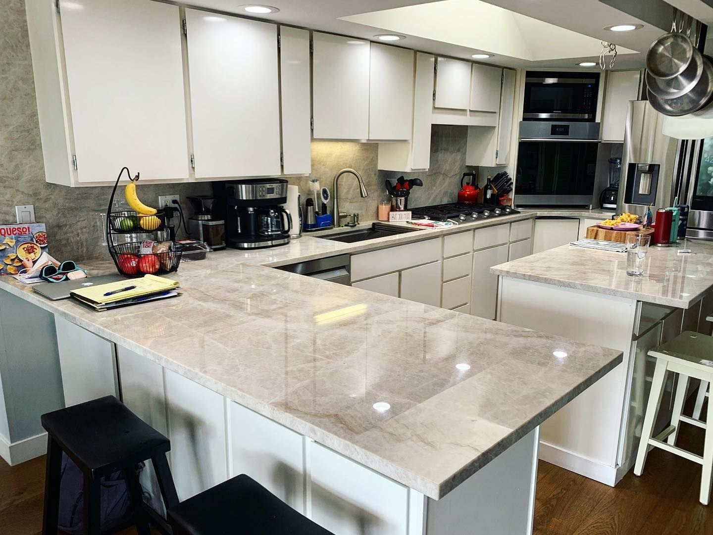 Bright kitchen with white cabinets, light countertops, and stainless steel appliances.