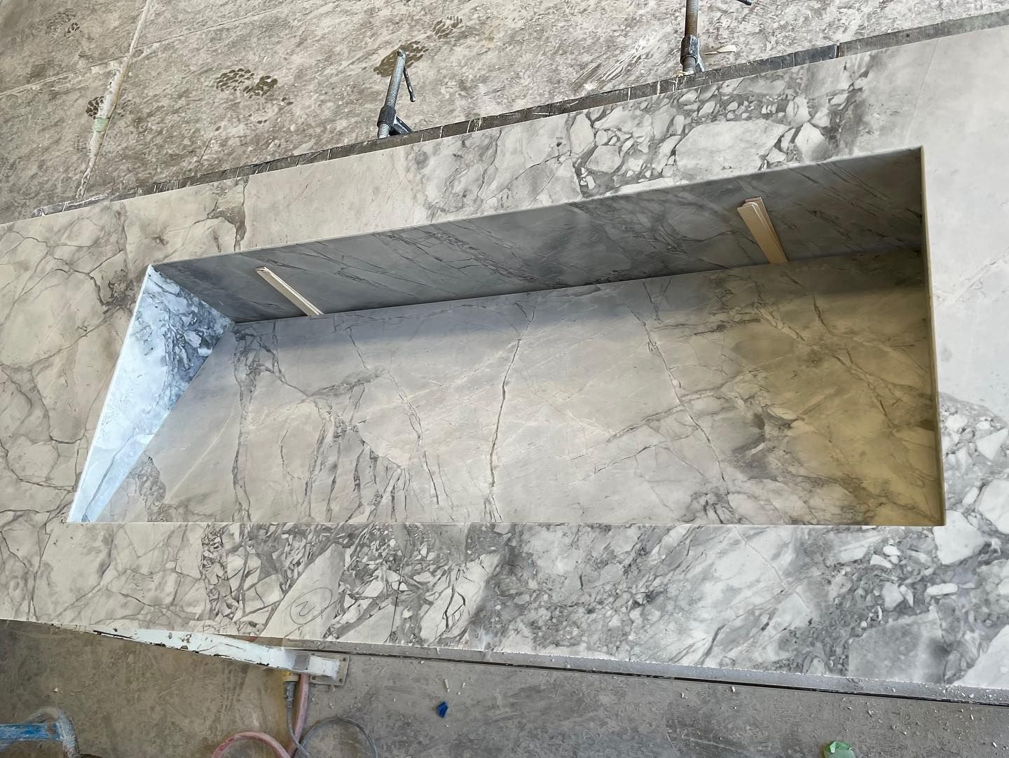 Marble countertop with a rectangular cut-out for a sink or built-in feature; grey veining.