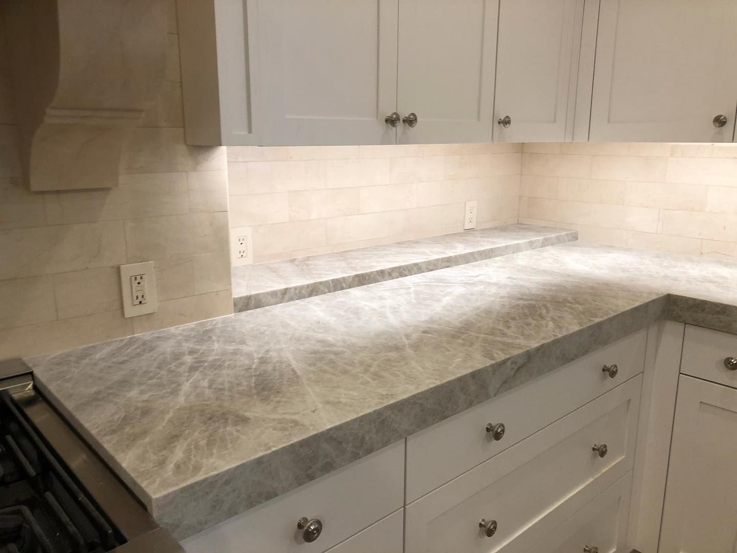 Kitchen with white cabinets, light gray marble countertop, and white tile backsplash.