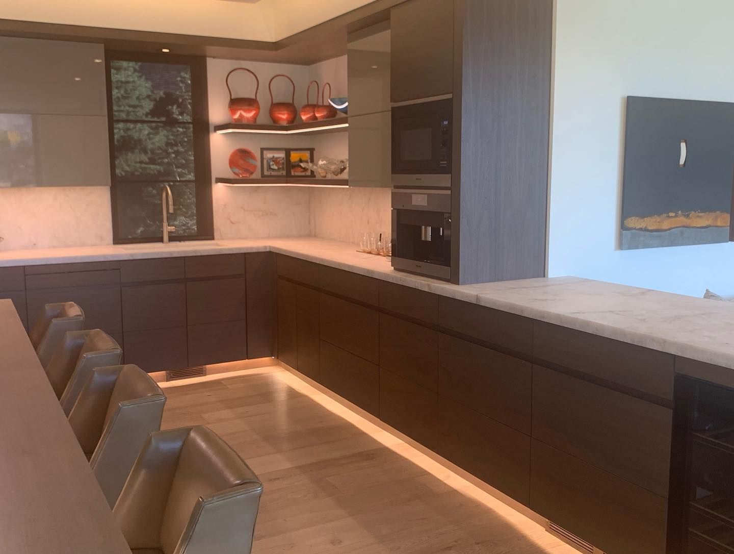 Modern kitchen with brown cabinets, white countertops, and under-cabinet lighting.