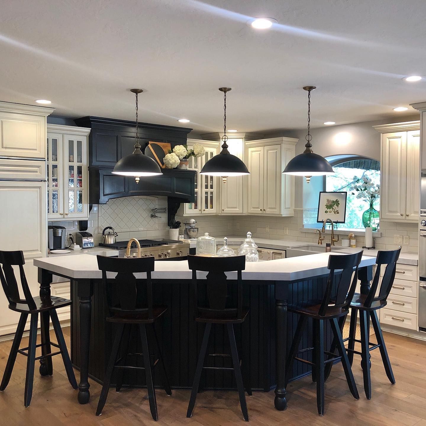 Kitchen with black and white cabinets, island with black stools, and pendant lights.