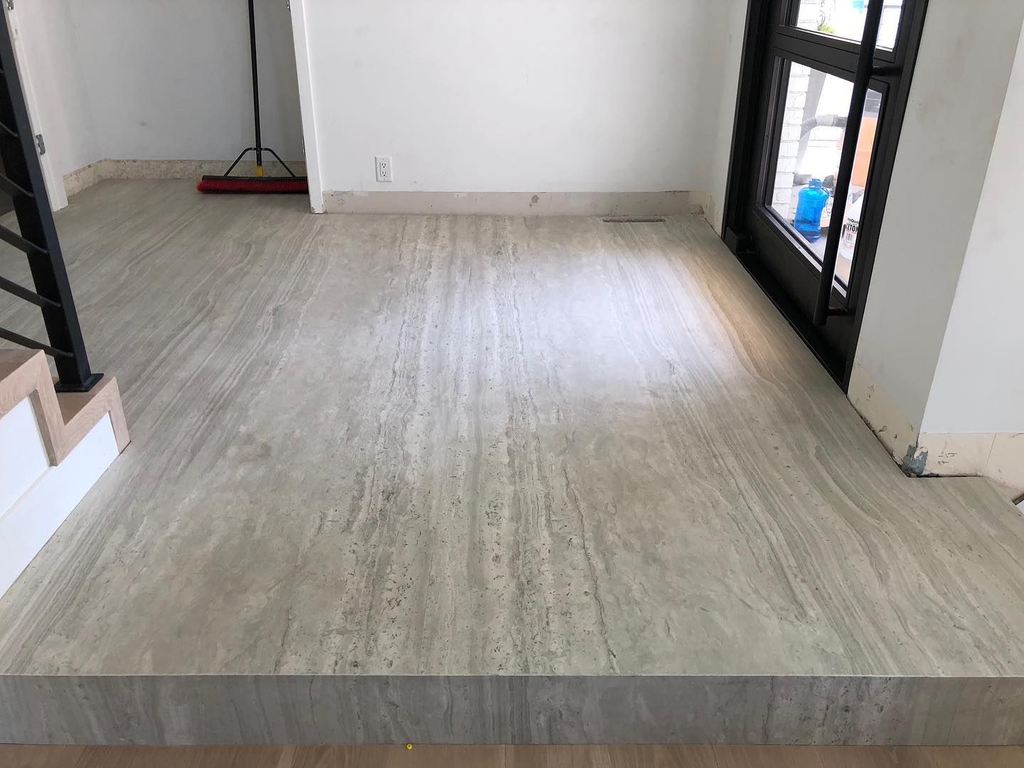 Beige tiled floor with a step up to a doorway and stairs on the left.