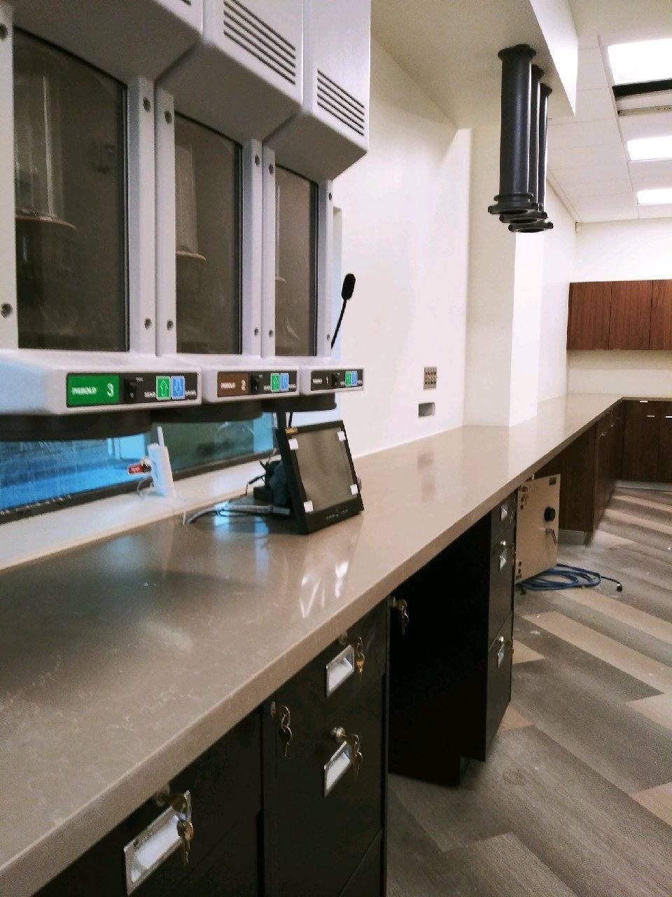 Laboratory workspace with gray countertop, cabinets, and equipment.
