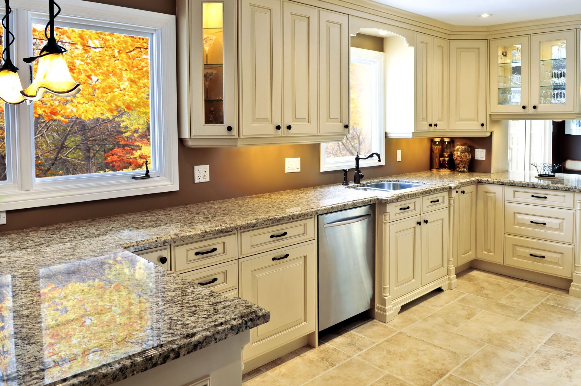 Cream-colored kitchen with granite countertops, stainless steel appliances, and a window with a fall foliage view.
