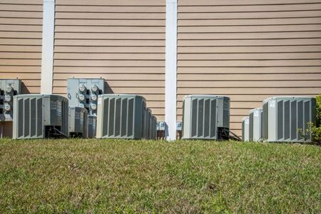 a row of air conditioners on the side of a house