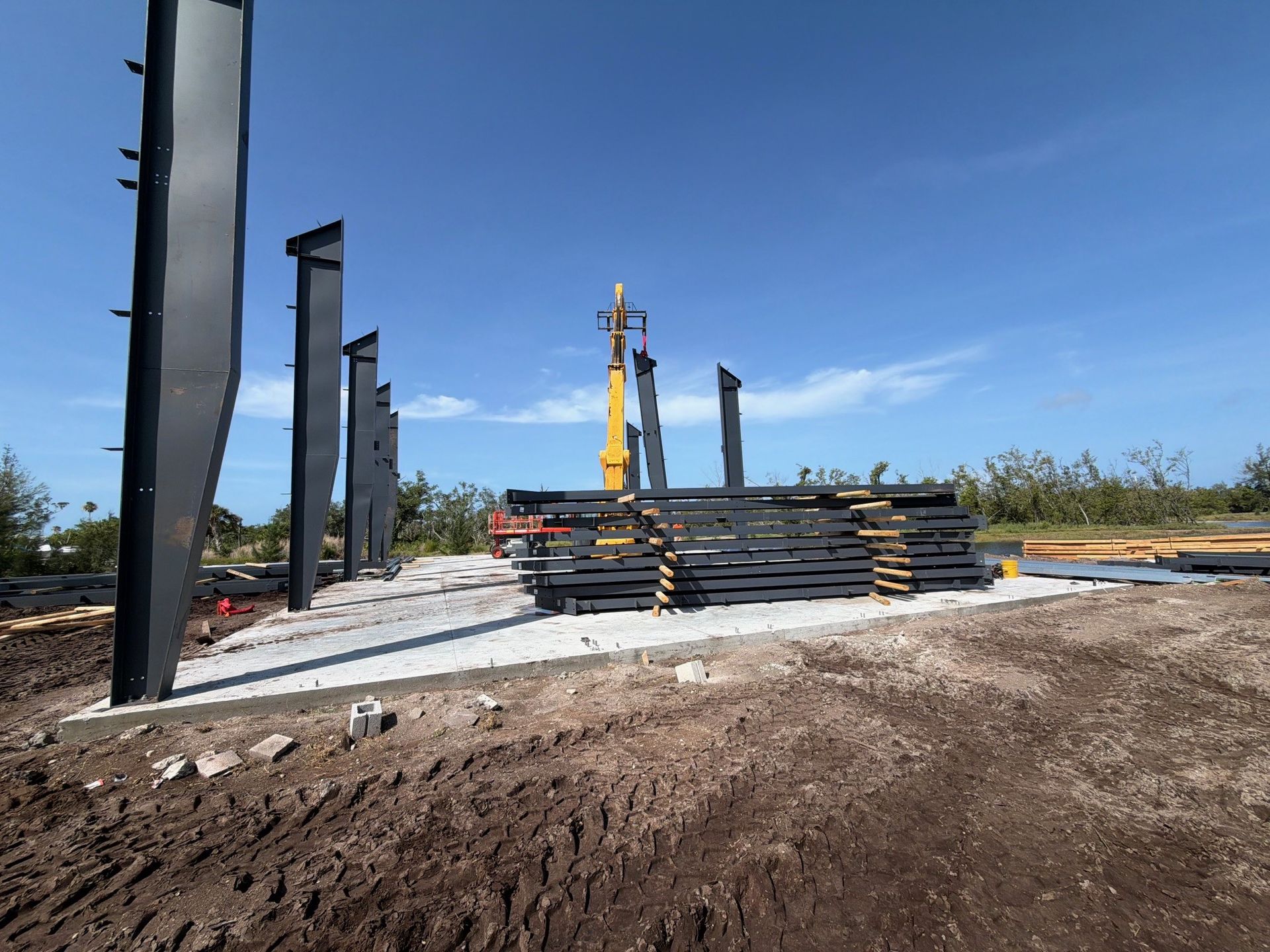 Construction workers assembling a large timber frame under a blue sky, with cranes and scaffolding nearby