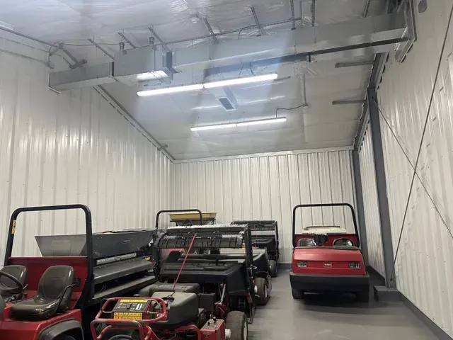 Several small cars parked inside a white enclosed garage or storage container.