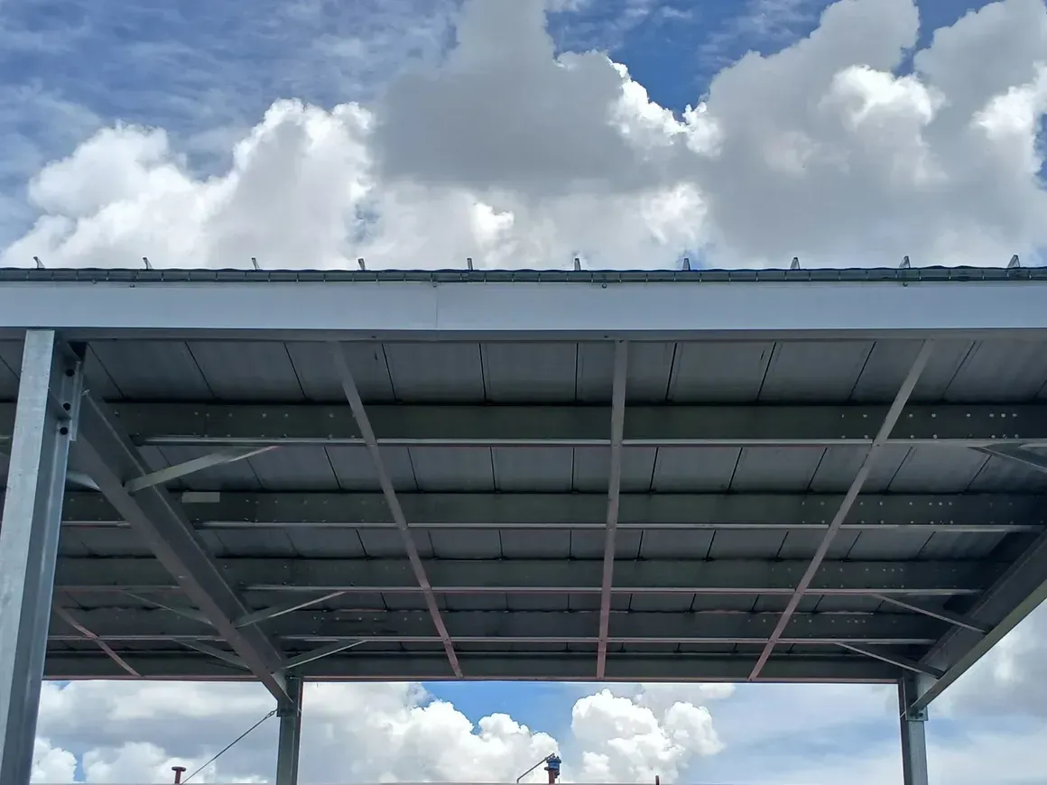 Metal carport roof under a cloudy blue sky