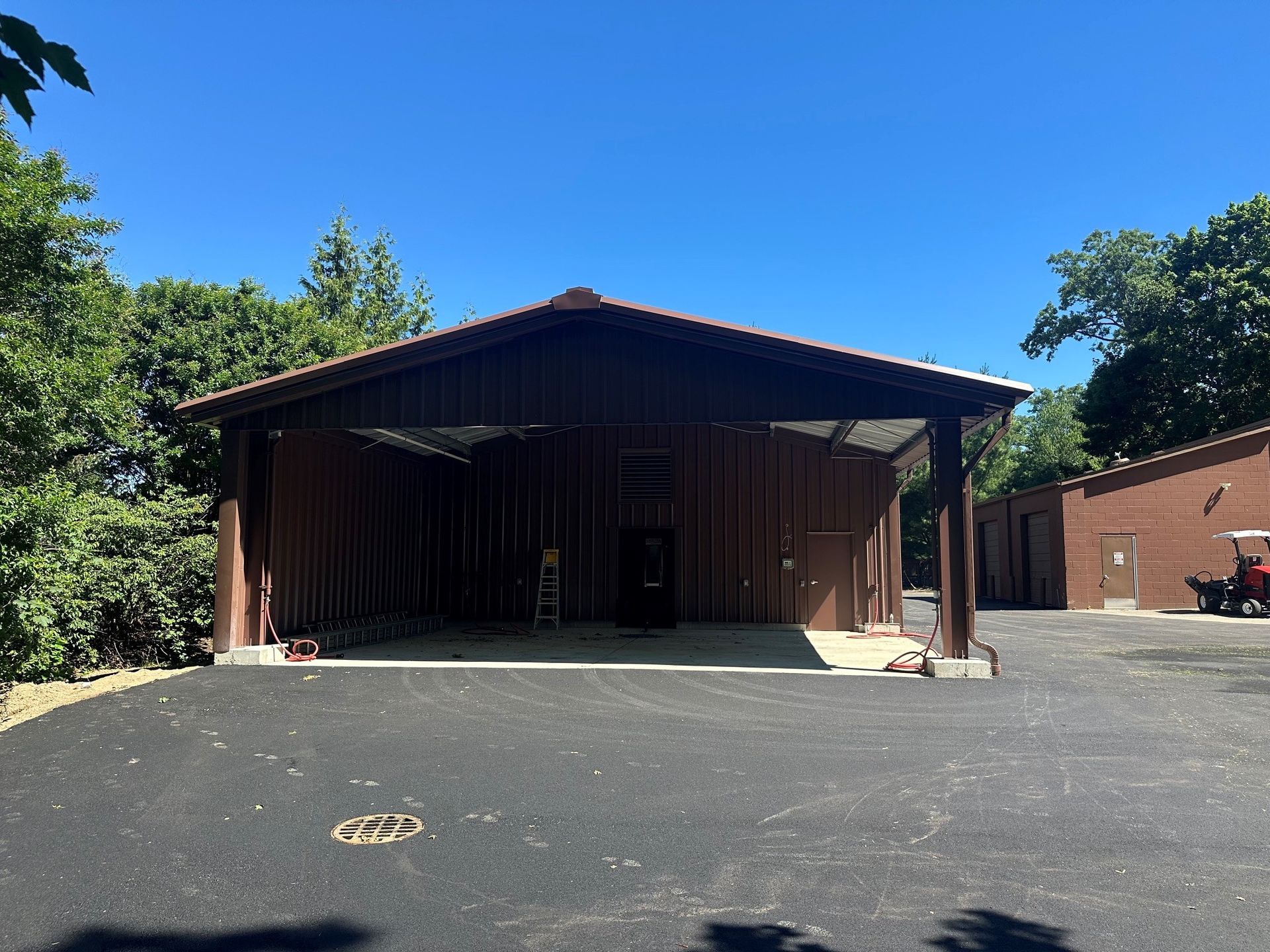 Small brown building with a covered porch and empty parking lot under a clear blue sky