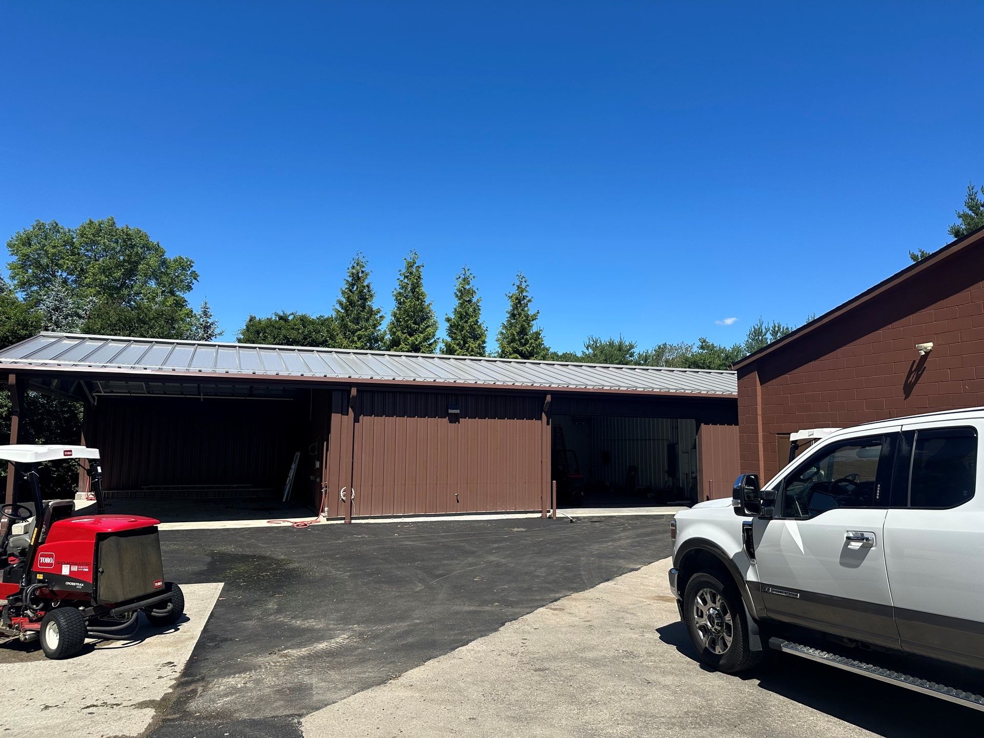 Two parked trucks beside a brown garage under a clear blue sky