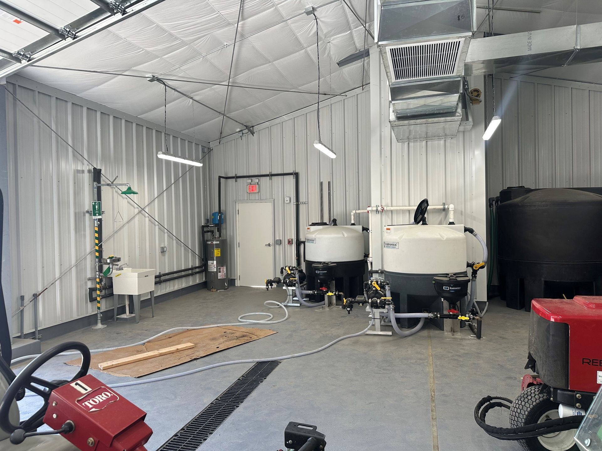 Industrial workshop interior with tanks, equipment, and a red machine on a concrete floor