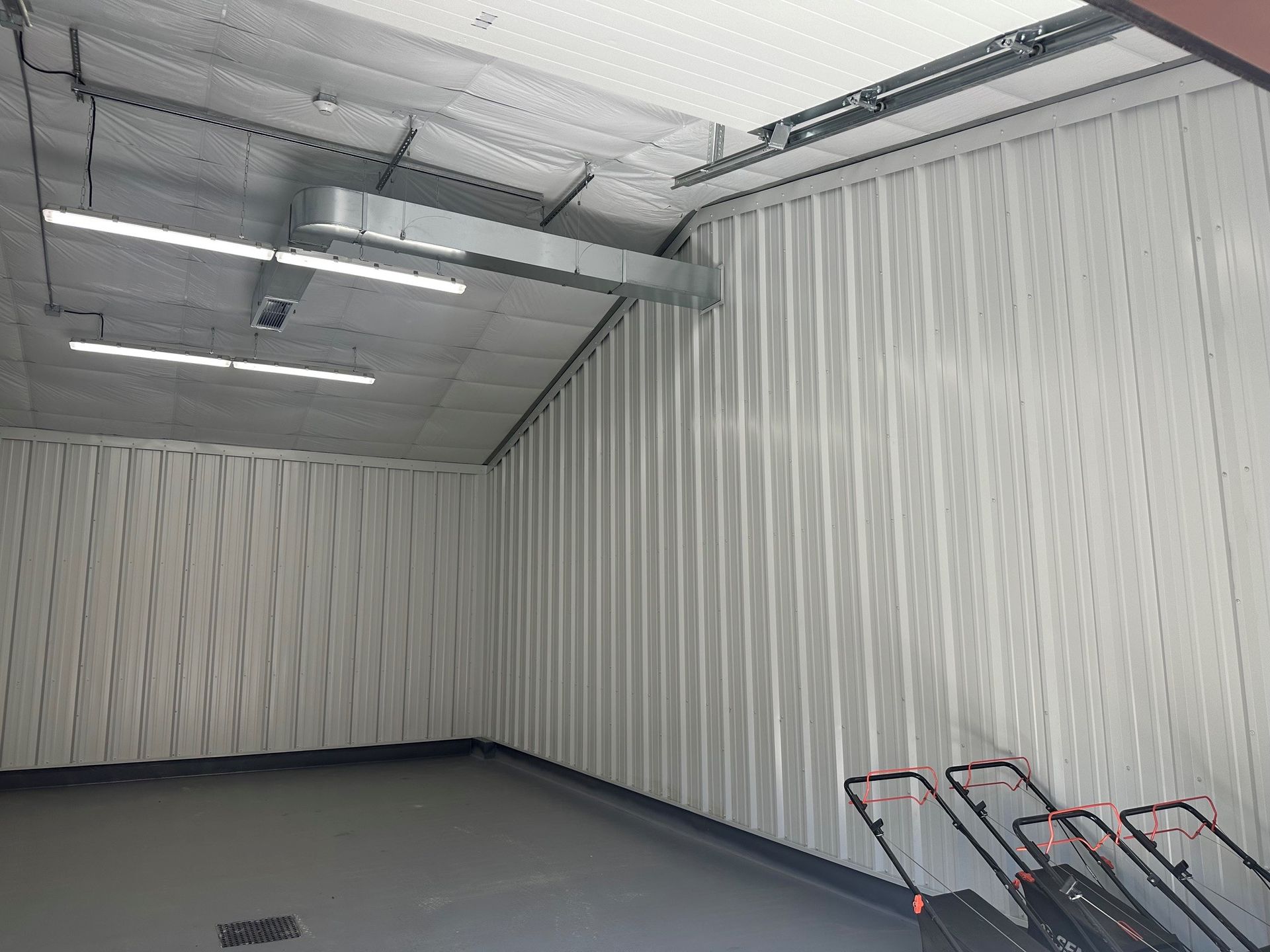 Empty warehouse interior with corrugated metal walls, fluorescent lights, and shopping carts in the corner