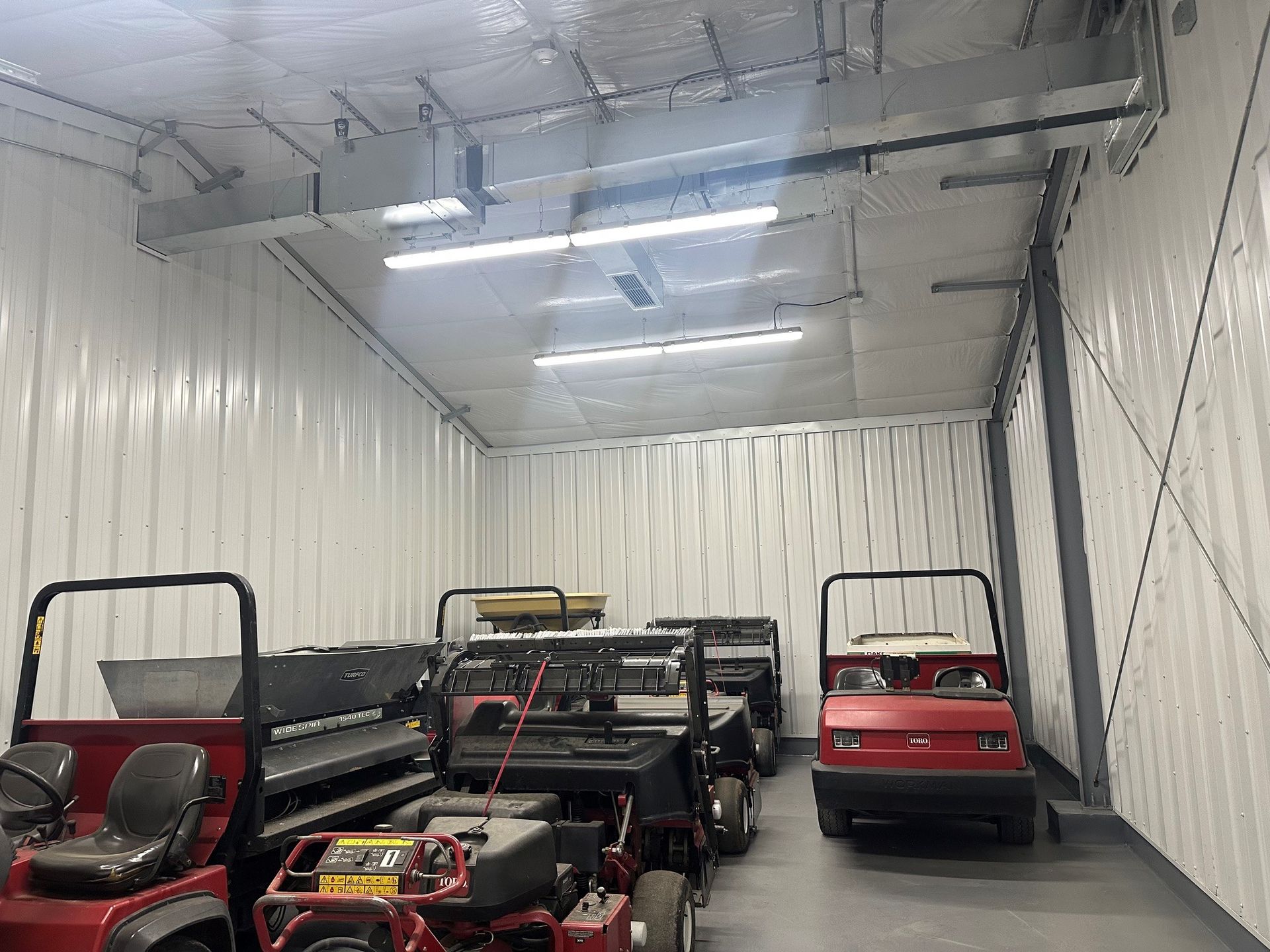 Several small utility vehicles parked inside a white-walled storage trailer
