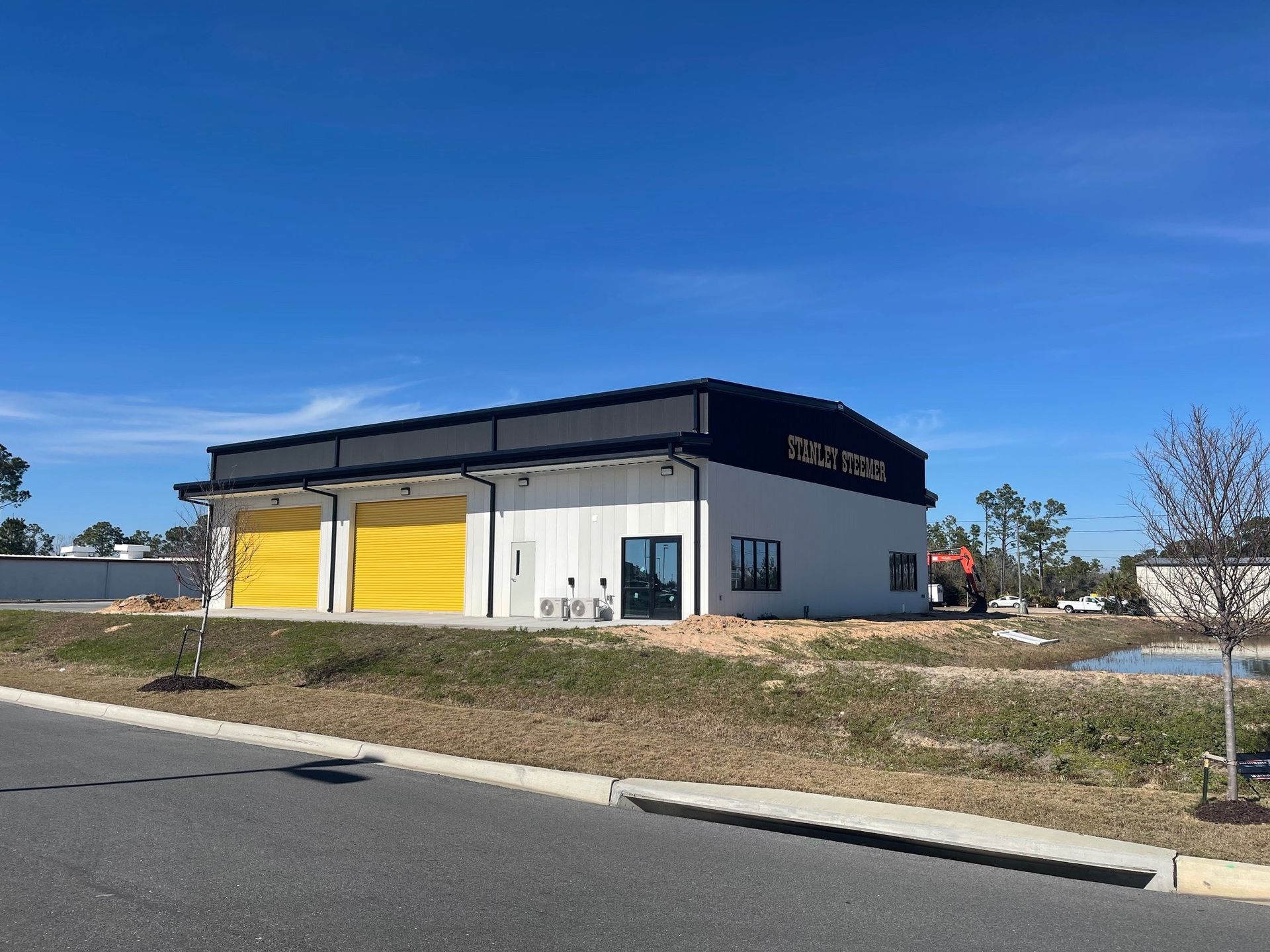 Modern commercial building with yellow garage doors under a blue sky