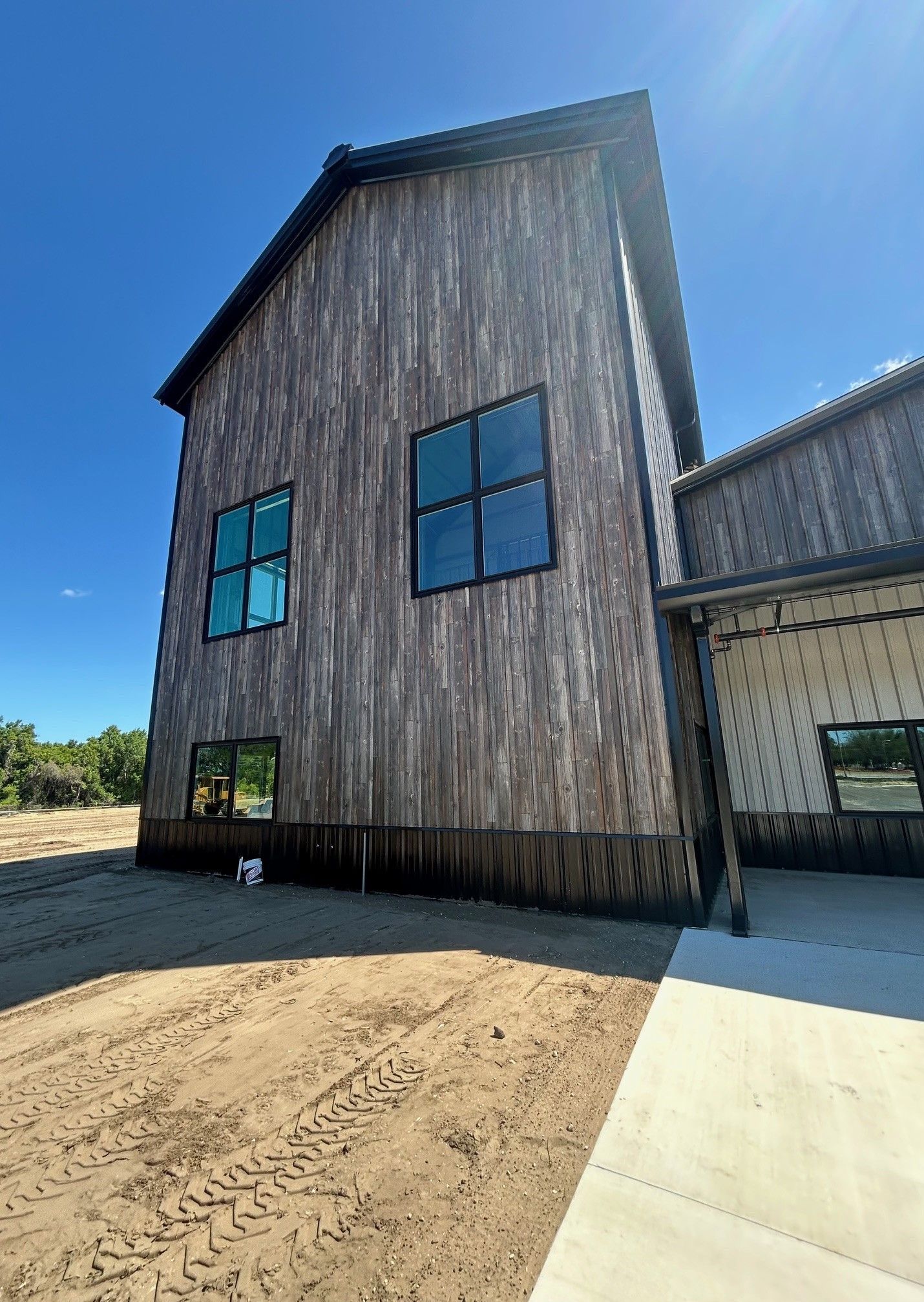 Weathered wooden barn-style building with blue-trimmed windows under a clear blue sky