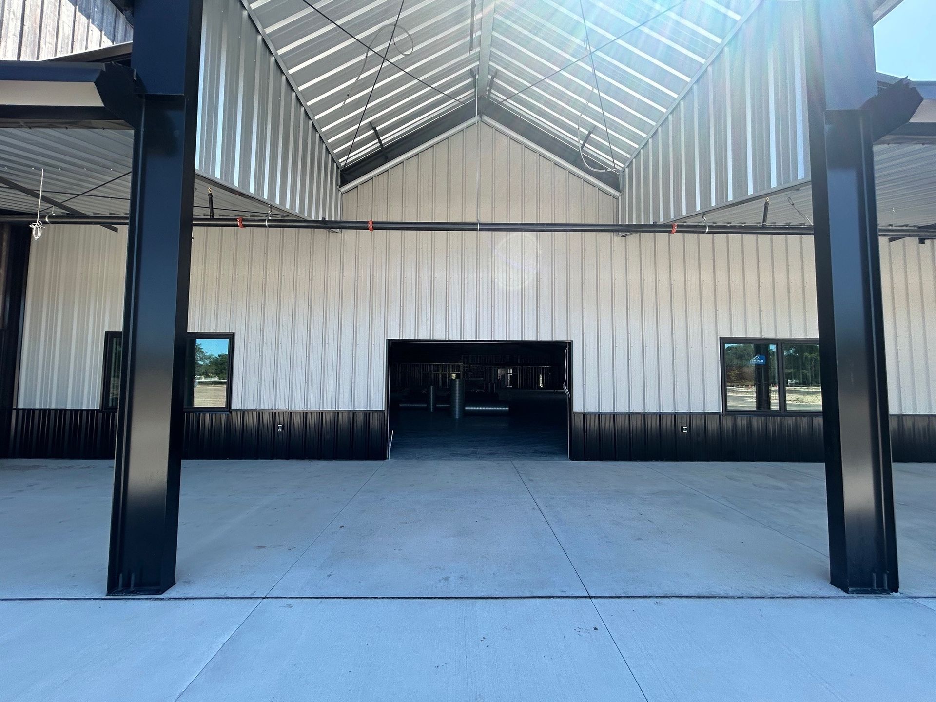 Modern building entrance with black columns, corrugated metal facade, and glass doors under a peaked roof