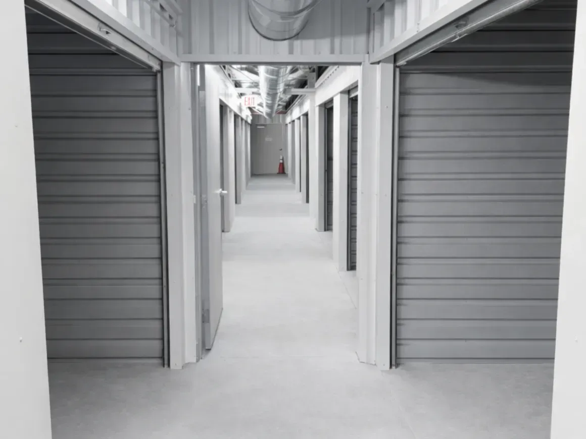 Interior storage facility hallway with open unit doors and closed gray roll-up doors