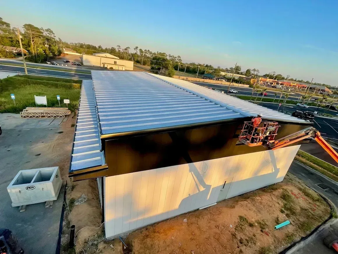 Aerial view of a small corrugated metal-roof building on a dry lot at sunset.