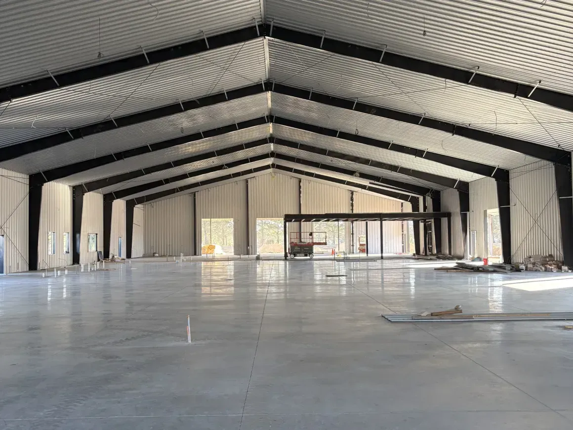 Empty industrial warehouse interior with high metal roof and concrete floor