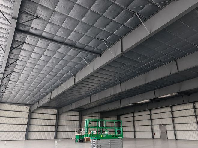 Empty warehouse interior with a green scissor lift under a high metal ceiling