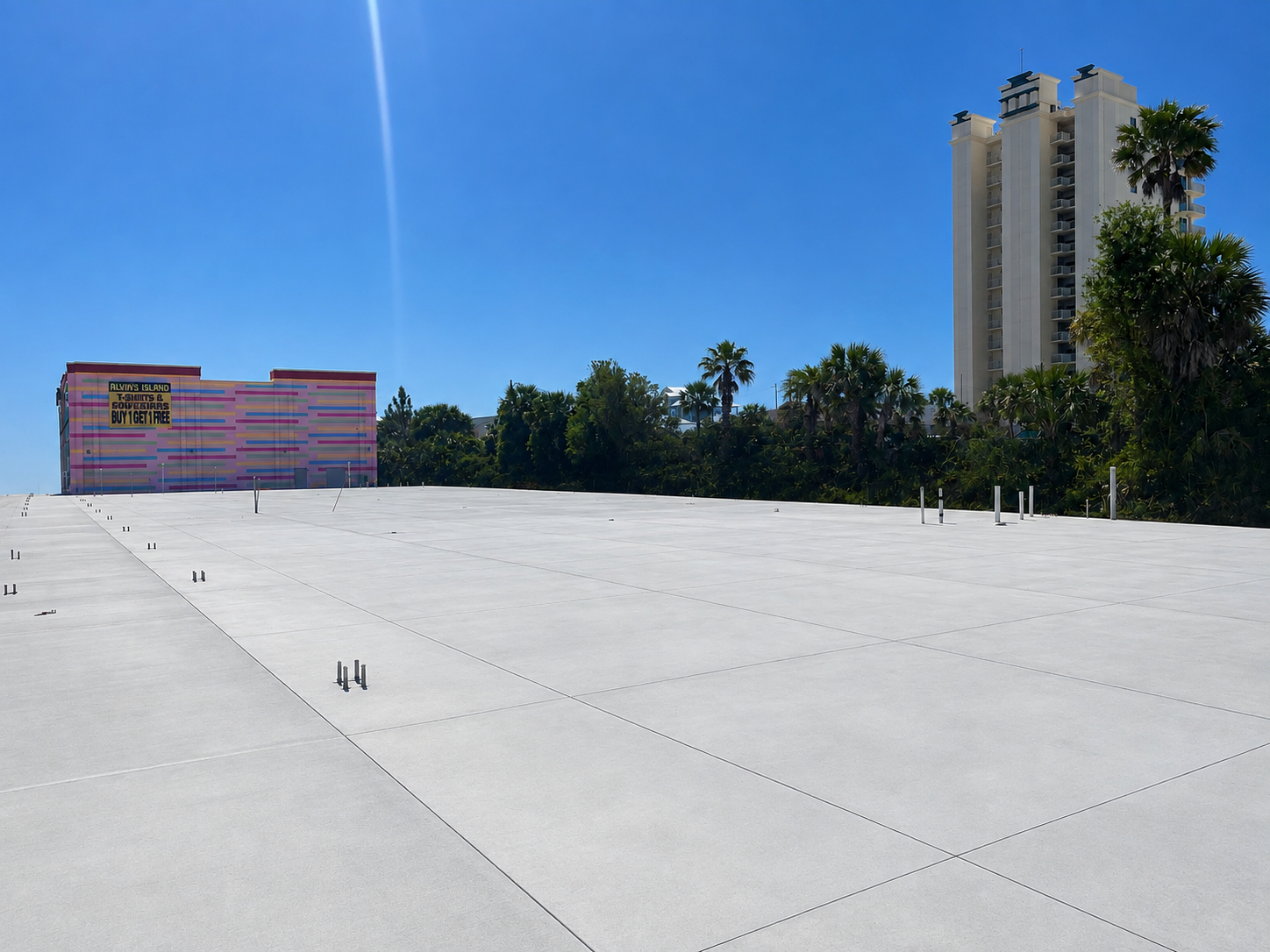 Empty rooftop with a bright sky, distant trees, and tall buildings on the horizon