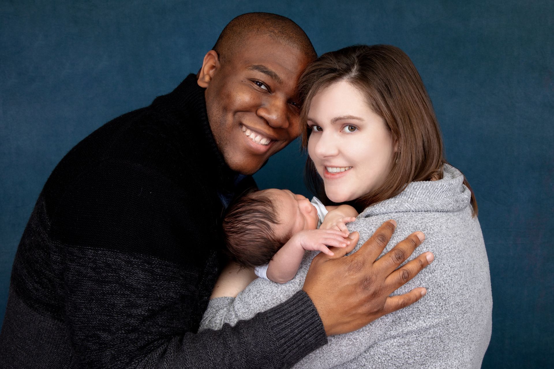 A man and a woman are holding a newborn baby.