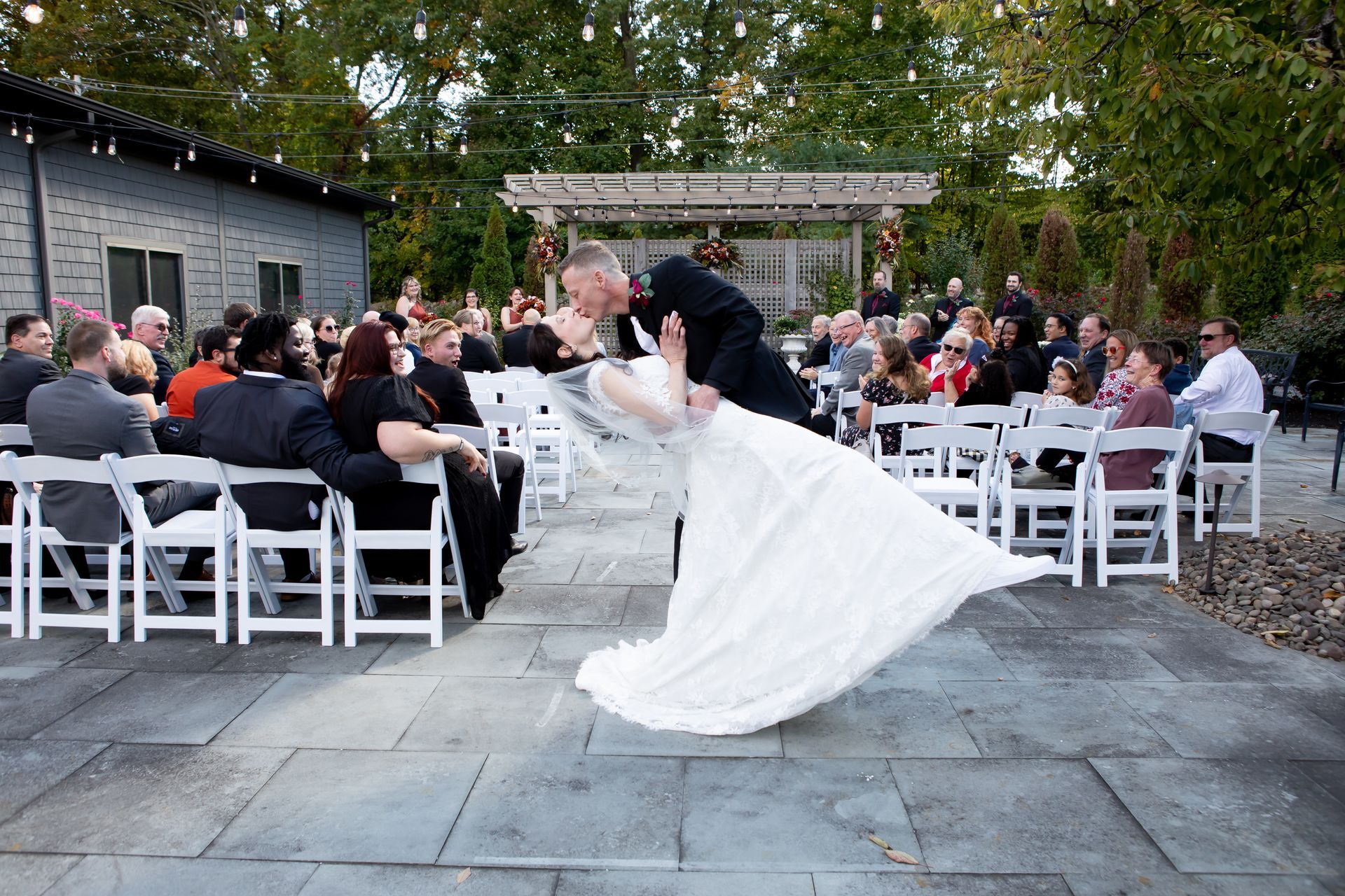 A bride and groom are kissing in front of their wedding guests.