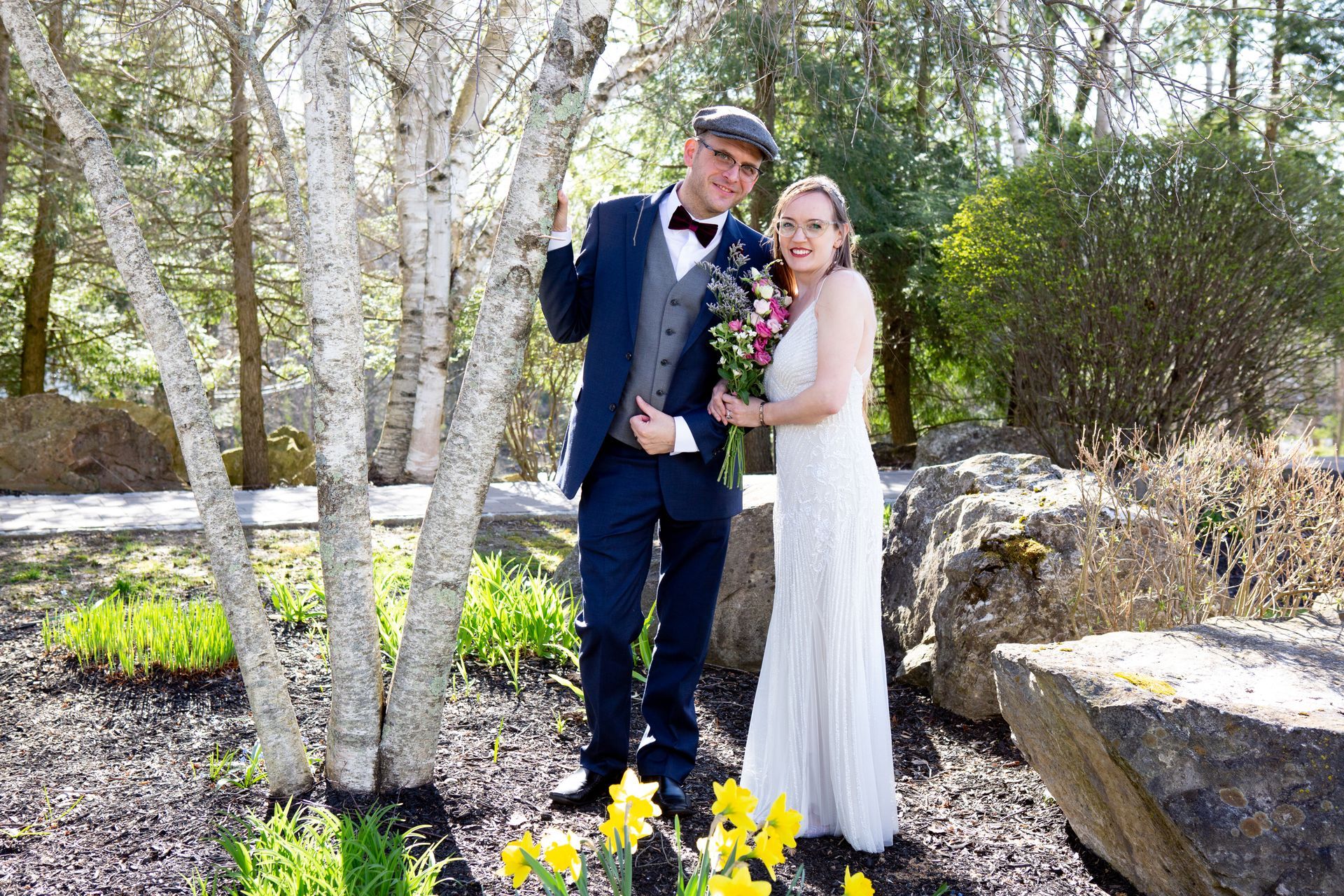 A bride and groom are posing for a picture in front of a tree.