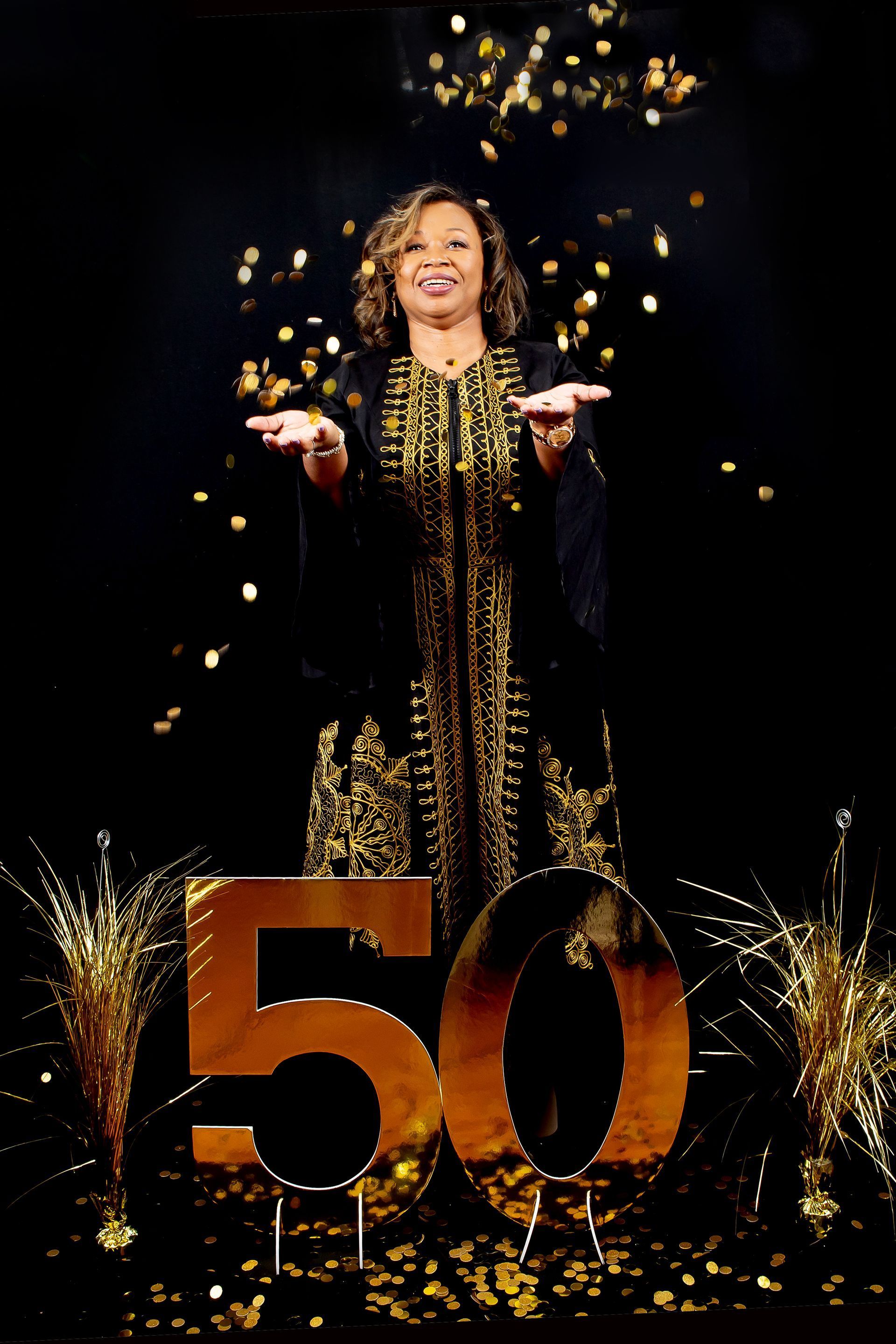 A woman in a black dress is standing in front of a 50 sign
