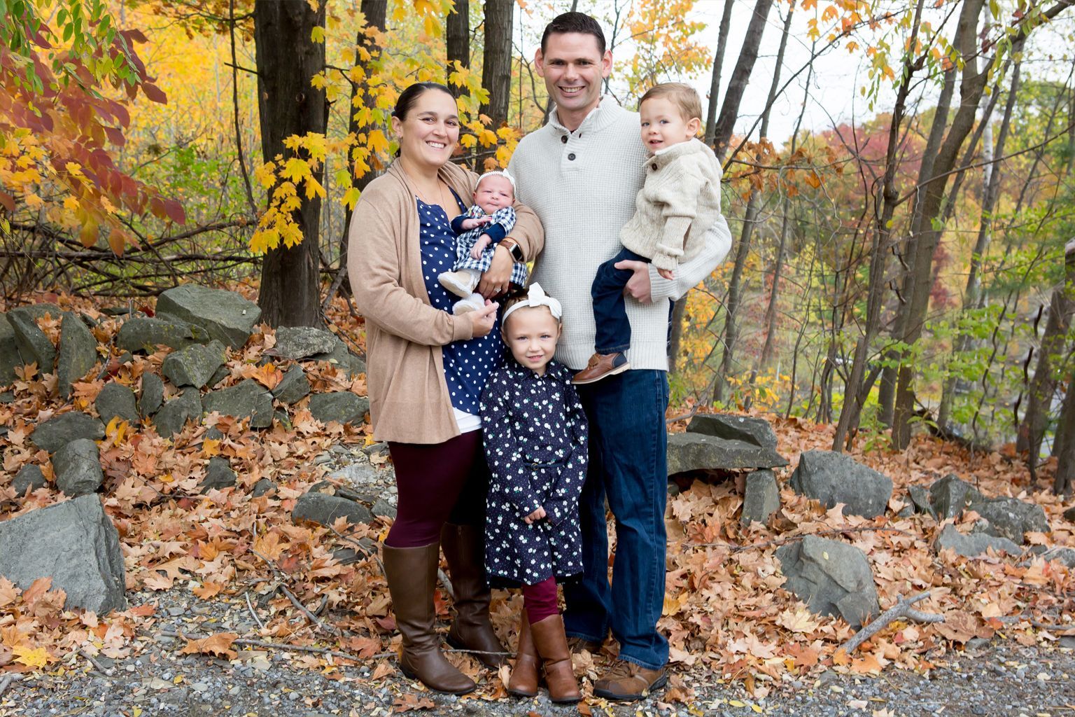 A family is posing for a picture in the woods.
