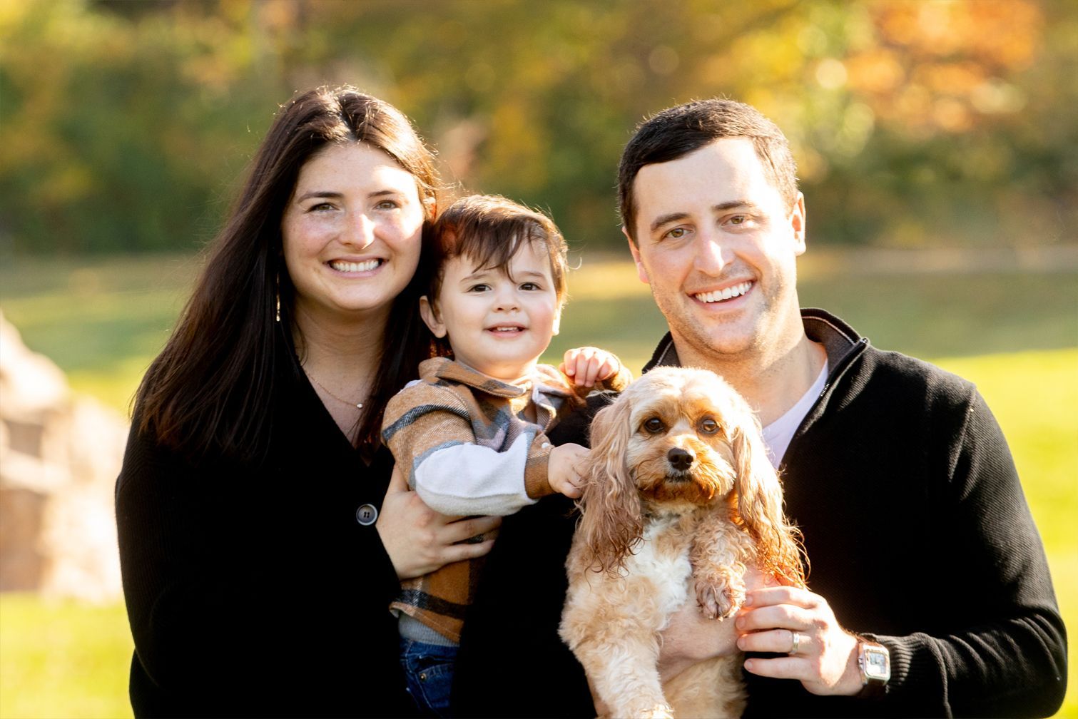 A family is posing for a picture with a dog.