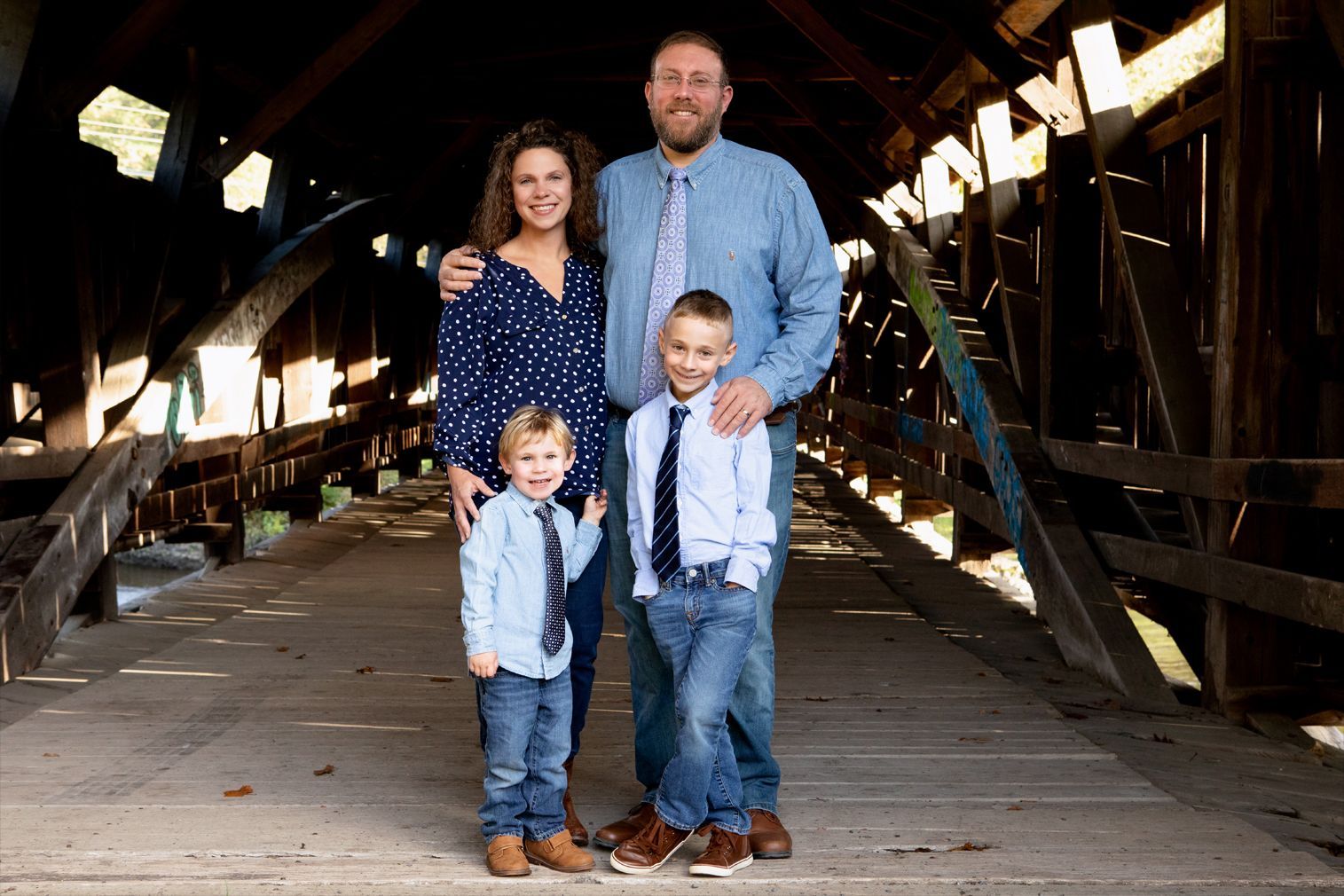 A family is posing for a picture on a bridge.