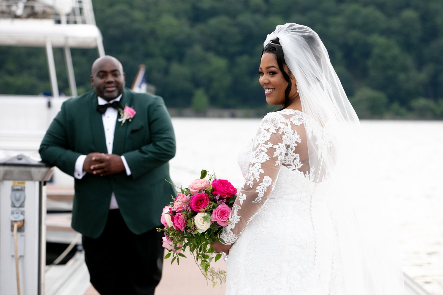 A bride and groom are standing next to each other on a dock.
