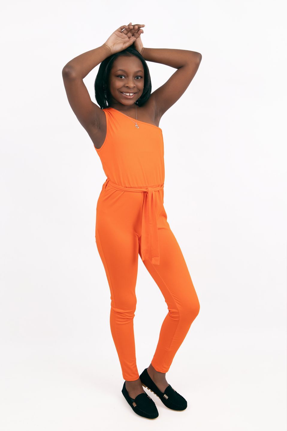 A woman is wearing an orange jumpsuit and black shoes.