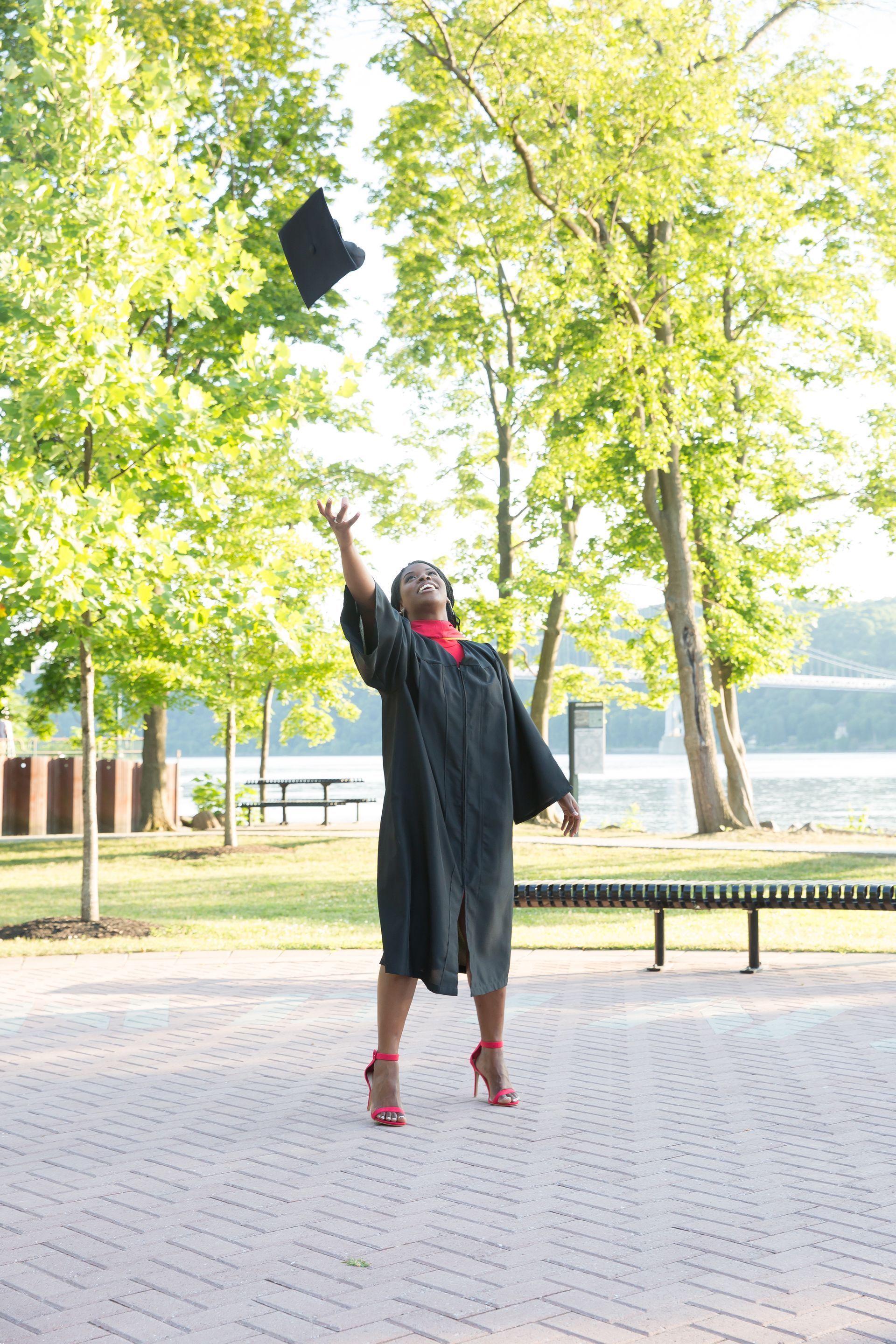 A woman in a graduation cap and gown is throwing her cap in the air.