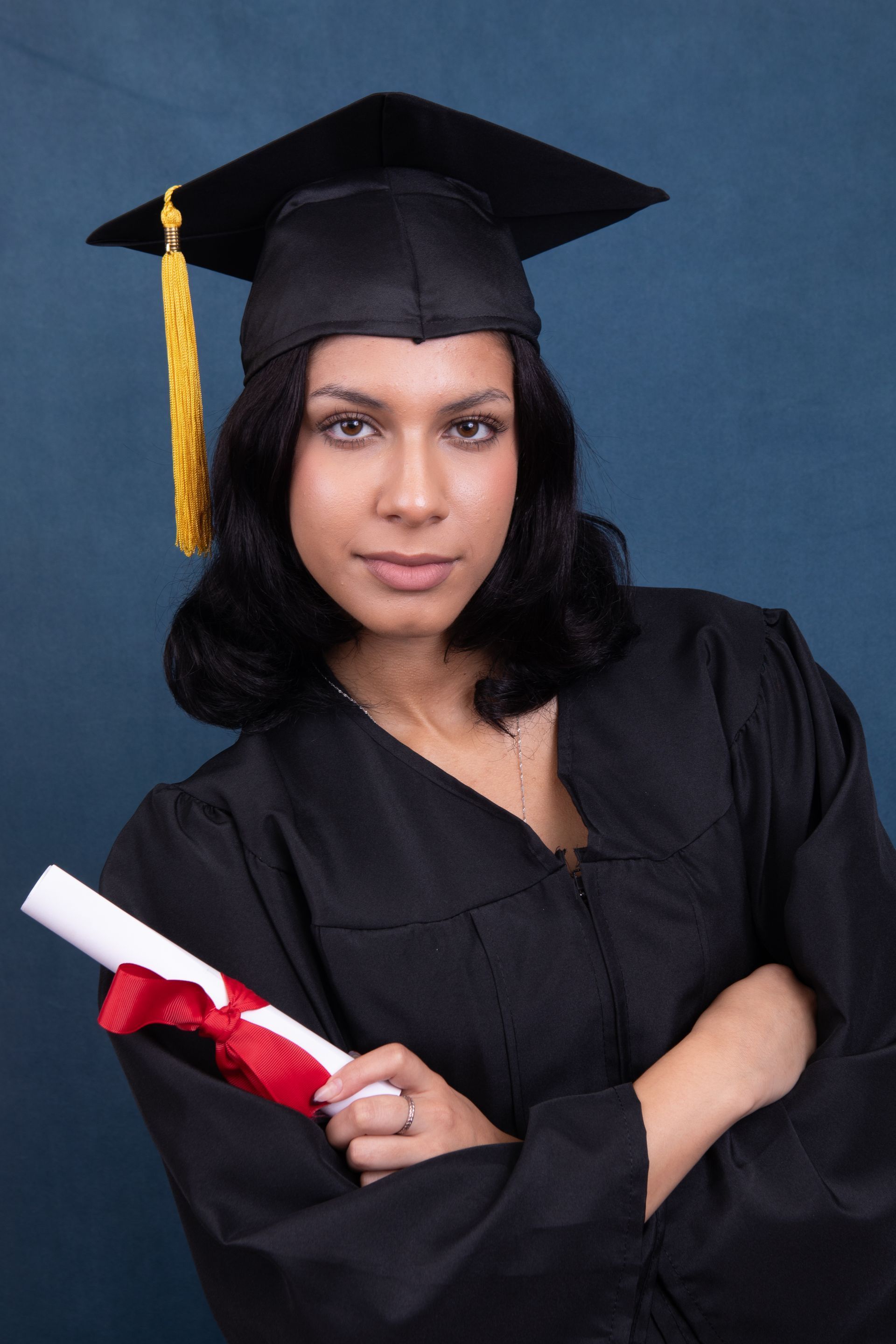 A woman in a graduation cap and gown is holding a diploma