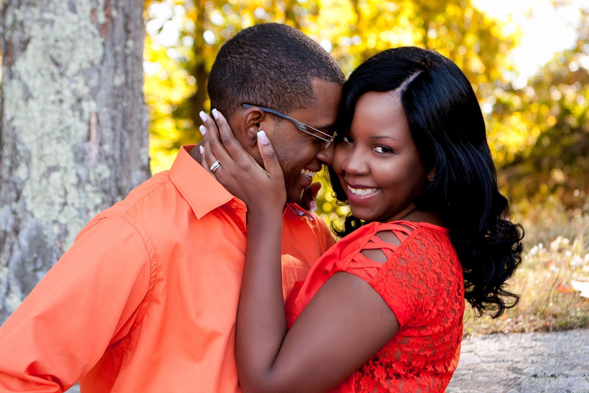 A man and a woman are posing for a picture, and the woman is wearing a red dress.
