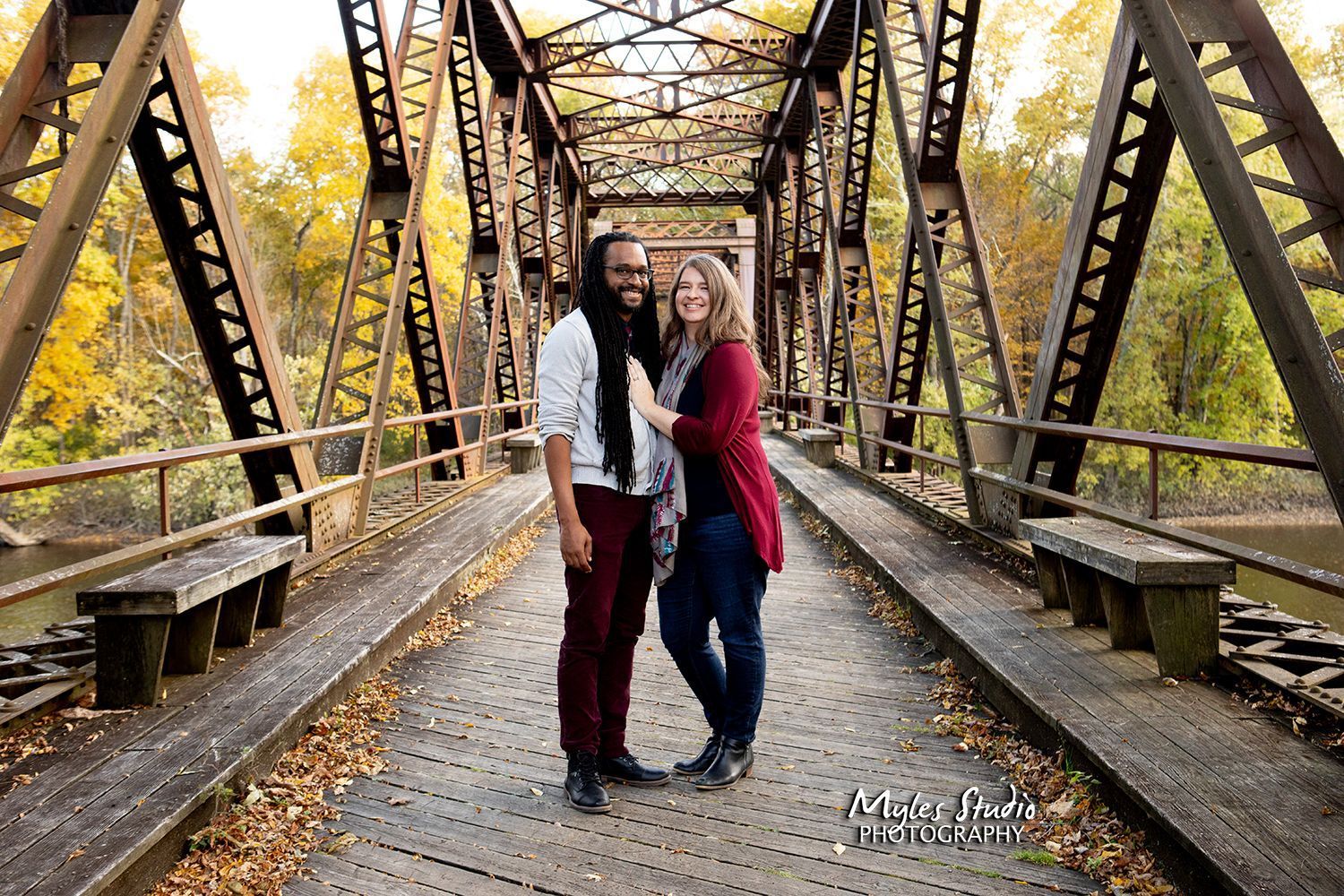 A man and a woman are posing for a picture on a bridge.