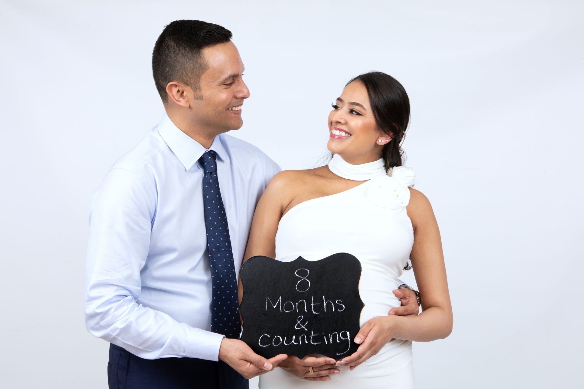 A man and a pregnant woman are holding a sign that says 8 months and counting.