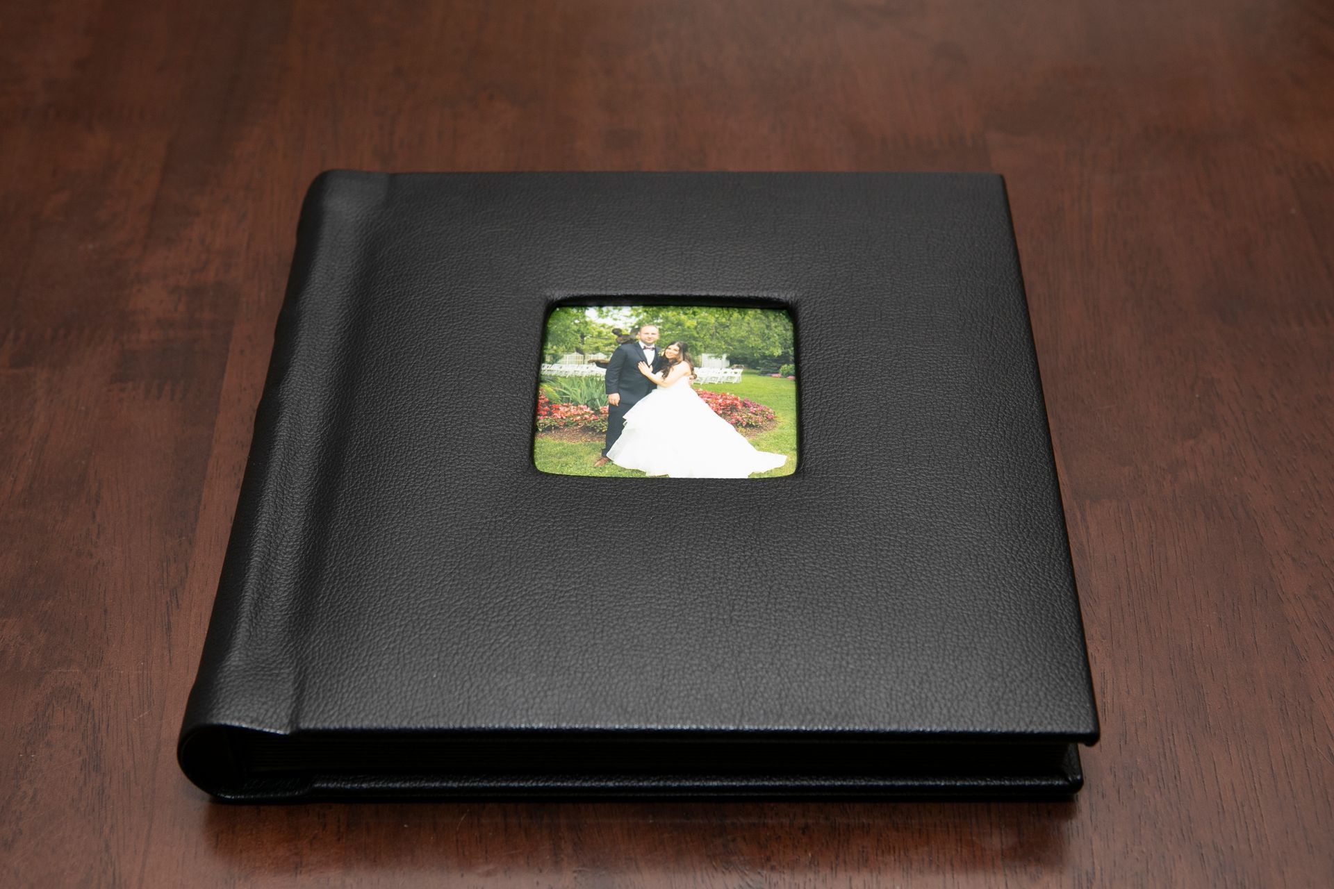 Black photo album with a wedding photo on a dark wooden surface.