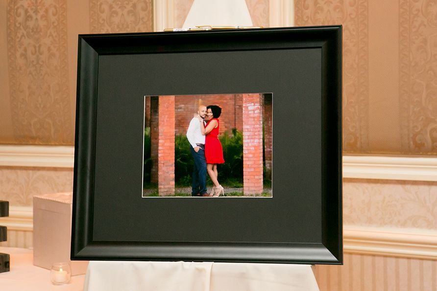 Framed photo on an easel on a brown wall backdrop.