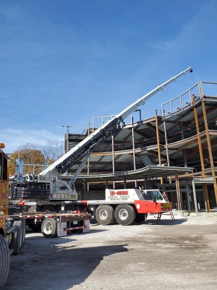 Construction crane lifting materials at a multi-story steel frame building under construction.