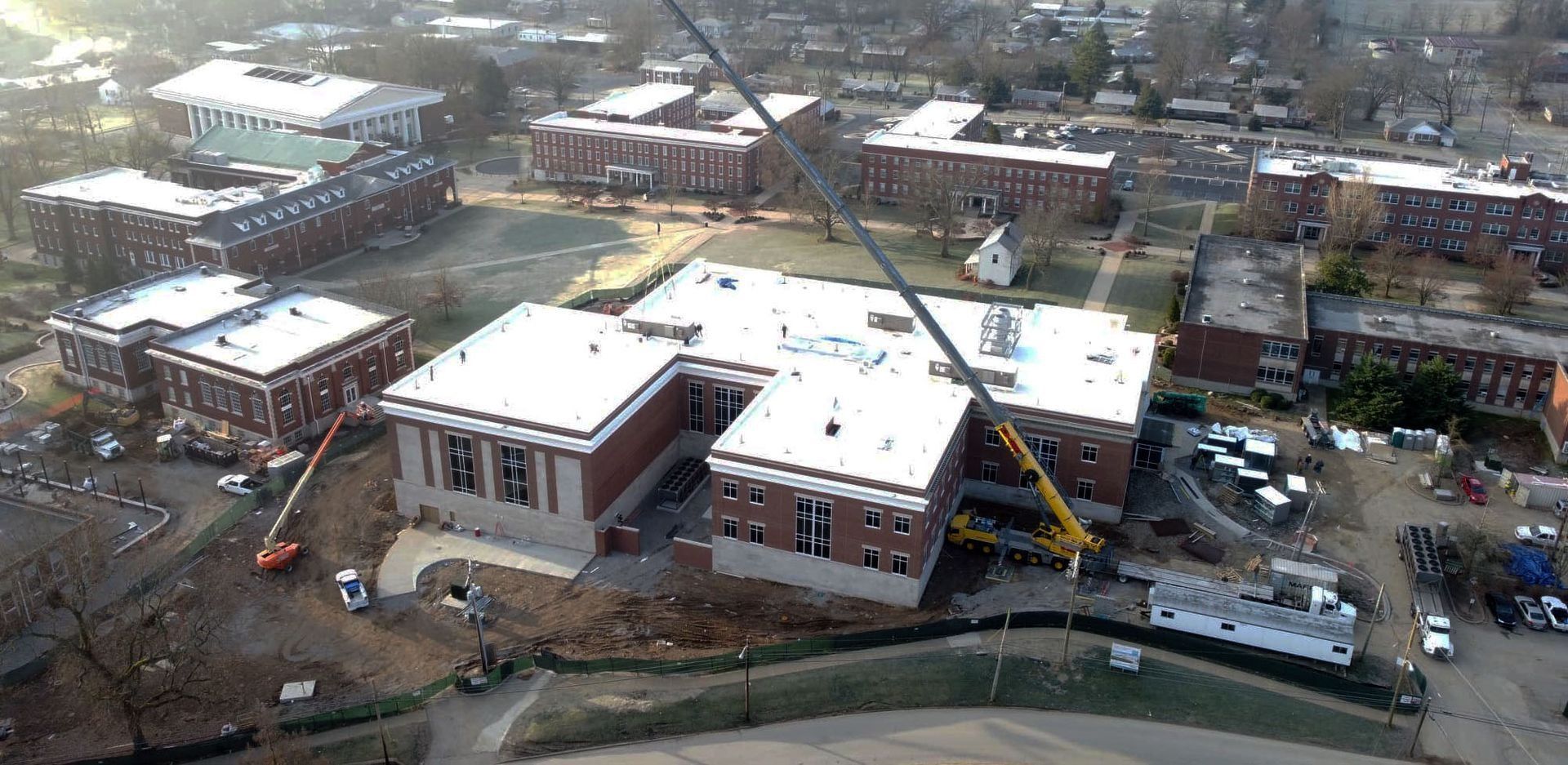 Aerial view of buildings under construction with a large crane on a campus.